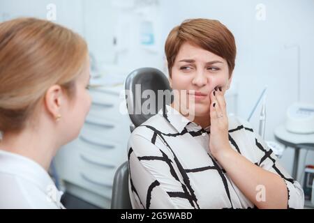 Junge Frau mit Zahnschmerzen, sitzt in Zahnarztstuhl in der Klinik Stockfoto