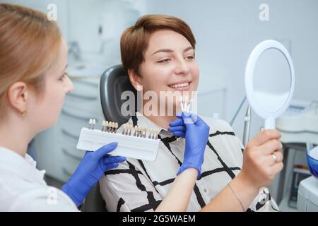 Zahnarzt hilft weiblichen Patienten, Zahnaufhellung Schatten aus der Tabelle zu holen Stockfoto