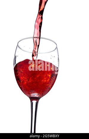 Gießt Rotwein in Glas auf weißem Hintergrund Stockfoto