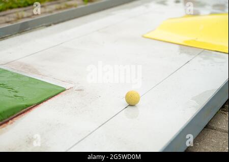 Nahaufnahme des gelben Balls auf dem Minigolfplatz nach Regen. Outdoor-Aktivitäten im Sommer. Stockfoto