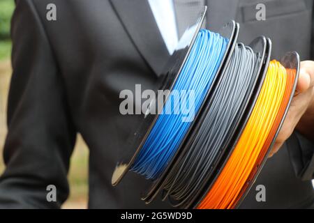 Mehrfarben-Drucker Filament Spulen aus Thermoplast, die aus erneuerbaren Quellen Nutzung Förderung Konzept von Mann in Anzug Hintergrund ist Stockfoto
