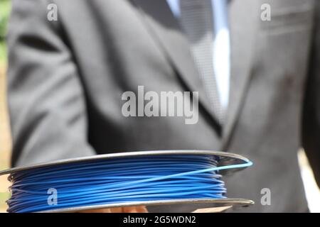 Das Filament des Druckers wird von Mann in Anzug gehalten und zeigt das Geschäftskonzept der Branche. PLA-Filament aus nachwachsenden Rohstoffen, die Art von Thermoplast ist Stockfoto
