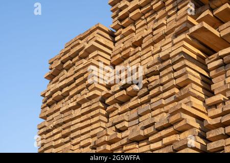 Holzstapel aus Kiefernholz aus natürlichen, rauen Holzbrettern auf der Baustelle. Industrielle Holzbaumaterialien Stockfoto