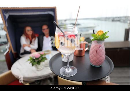 30. Juni 2021, Mecklenburg-Vorpommern, Kühlungsborn: Auf der Terrasse des Restaurants Vielmeer am Bootshafen serviert Ibrahim Hussein Gäste, die in einem Strandstuhl sitzen. Der Neubeginn von Gastronomie und Tourismus nach monatelanger Corona-Zwangspause hat dem Arbeitsmarkt in Mecklenburg-Vorpommern einen starken Schub gegeben. Für den Monat Juni meldete die Nord-Regionaldirektion der Bundesagentur für Arbeit in Kiel am Mittwoch bundesweit 61,600 Arbeitslose. Das waren 4800 weniger als im Vormonat Mai und 4300 weniger als im Juni 2020. Foto: Bernd Wüstneck/dpa-Zentralbild/dpa Stockfoto