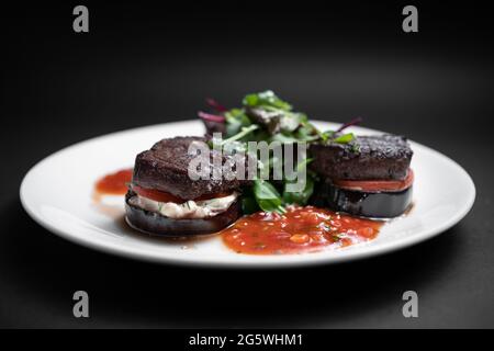 Nahaufnahme von Fleischrindmedaillon auf Tomate und gegrillter Aubergine mit Salsa-Sauce Stockfoto