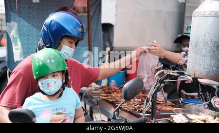 Vater und Tochter auf einem Motorrad Klong Toey Market Wet Market Bangkok Thailand Geld wechseln die Hände Stockfoto