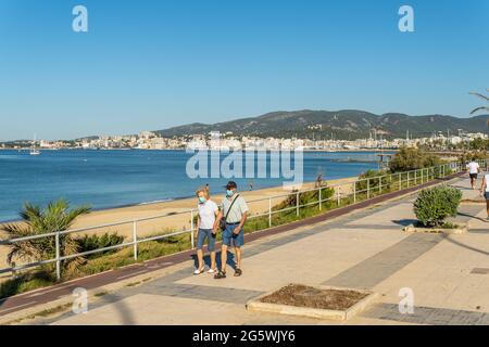 Palma de Mallorca, Spanien; 25 2021. juni: Älteres Paar, das bei Sonnenaufgang mit einer Gesichtsmaske entlang der Promenade von Palma de Mallorca läuft. Coronavirus pande Stockfoto