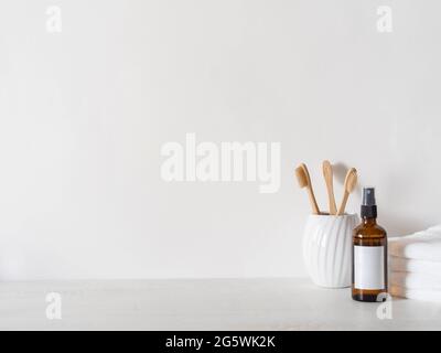 Bernsteinglasflasche mit weißem Ablabel, Bambuszahnbürsten und weißen Handtüchern auf weißem Hintergrund. Vorderansicht. Minimaler Badehintergrund. Speicherplatz kopieren Stockfoto