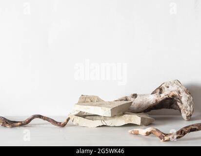 Graue Natursteine Podium und Treibholz auf weißem Hintergrund, Plattform für Produktdisplay. Rohling für Mockup-Design. Vorderansicht. Speicherplatz kopieren Stockfoto
