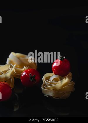 Ungekochte italienische Pasta Fettuccine nisten auf schwarzem Hintergrund. Hausgemachte Pasta. Italienische Küche. Eiernudeln. Stockfoto