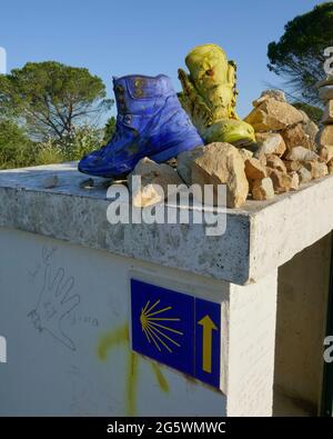 Alte, gelb und blau lackierte Stiefel, links als Wanderzeichen auf dem Camino de Santiago Stockfoto