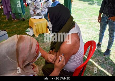 Srinagar, Indien. 30. Juni 2021. Ein Gesundheitsmitarbeiter impft eine Transgender-Person mit einer Dosis des Covishield-Impfstoffs gegen das Covid-19-Coronavirus in einem Park in Srinagar ein. Kredit: SOPA Images Limited/Alamy Live Nachrichten Stockfoto