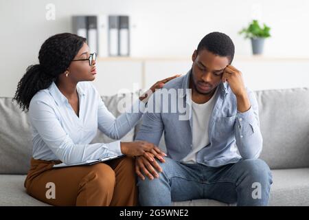Verärgert schwarzen Kerl, der an Depressionen leidet, unterstützt ihn sein Berater im Büro Stockfoto