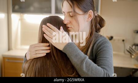 Junge Mutter küsst und umarmt aufgeregt weinende Tochter nach dem Gespräch über Probleme. Eltern unterstützen und trösten Kind Stockfoto