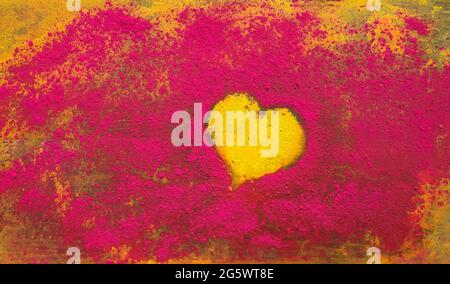 Gelbe Herzform, umgeben von rotem pulverförmiges Farbpigment. Stockfoto