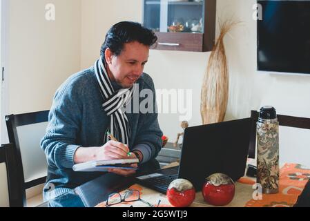 Hombre escribiendo en la mesa de madera planificando el analisis de negocio con la Laptop, venta,compra, Internet desde casa. Stockfoto