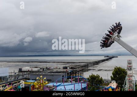 Southend on Sea, Essex, Großbritannien. Juni 2021. Trotz des bewölkten Wetters mit zeitweiligen Regenfällen sind die Attraktionen am Meer und die aufregenden Fahrten vor allem bei jungen Menschen beliebt geblieben. Im Adventure Island Themenpark an der Strandpromenade können Sie beobachten, wie sich über die Themsemündung Regenwolken den Axis Riders nähern Stockfoto