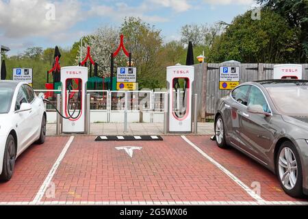 Elektroautos, die mit dem Tesla-Kompressor verbunden sind, stehen in Parkbuchten an der Welcome Break-Anlage an der Autobahn-Tankstelle M42 Alvechurch Birmingham UK Stockfoto