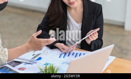 In einem Schnitt wurden Geschäftsleute mit einem digitalen Tablet aufgenommen und im Messraum über Geschäftsdaten diskutiert. Stockfoto