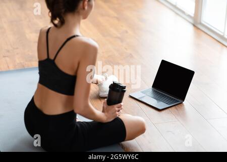 Junge Frau sitzt auf der Matte mit pc Stockfoto