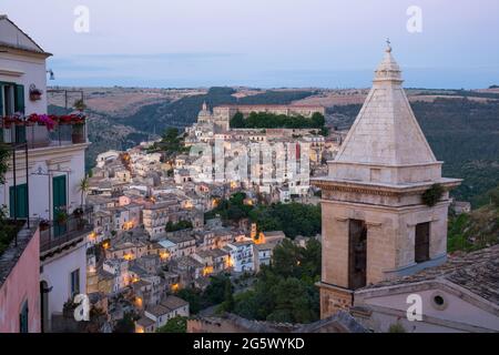 Ragusa, Sizilien, Italien. Blick über das Tal zu den Dächern von Ragusa Ibla, Dämmerung, Glockenturm der Kirche Santa Maria delle Scale im Vordergrund. Stockfoto