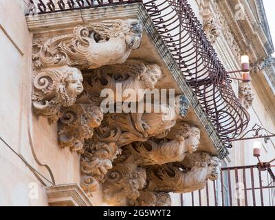 Noto, Syrakus, Sizilien, Italien. Fein geschnitzte Steinfiguren, die einen dekorativen Balkon auf der barocken façade des Palazzo Nicolaci di Villadorata stützen. Stockfoto