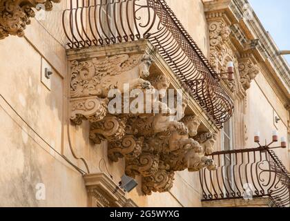 Noto, Syrakus, Sizilien, Italien. Fein geschnitzte Steinfiguren, die einen dekorativen Balkon auf der barocken façade des Palazzo Nicolaci di Villadorata stützen. Stockfoto