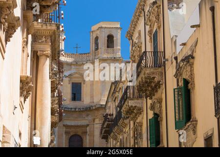 Noto, Syrakus, Sizilien, Italien. Blick entlang der historischen Via Corrado Nicolaci auf die façade und den östlichen Glockenturm der Kirche von Montevergine. Stockfoto