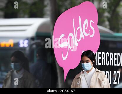 Paris, Den 30. Juni. Juli 2021. Eine Frau kommt an Plakaten über Sommerverkäufe vor dem Kaufhaus der Galerie Lafayette in Paris, Frankreich, 30. Juni 2021 vorbei. Die 4-wöchige Sommerverkaufssaison 2021 startete hier am Mittwoch und dauert bis zum 27. Juli 2021. Kredit: Gao Jing/Xinhua/Alamy Live Nachrichten Stockfoto