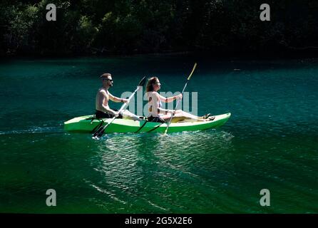 Junge Leute kühlen sich an einem heißen Sommertag in den Oregon Cascades in einem Kajak für zwei Personen auf dem Clear Lake ab. Stockfoto