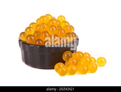 Gelbe Tapiokaperlen für Bubble Tea isoliert auf weißem Hintergrund. Tapioka-Perlen in schwarzer Keramikschale. Stockfoto