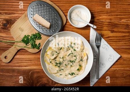 Ravioli mit Pilzen, Parmigiano, Petersilie und frischem Basilikum. Holztisch-Anordnung. Nahaufnahme. Draufsicht Stockfoto