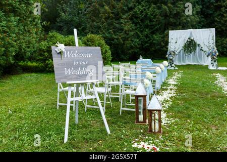 Hochzeitszeremonie Dekorationen: Bogen, Stühle, Zeiger und viele Blumen in weiß und blau Stil, auf einem Hintergrund von Grün Stockfoto