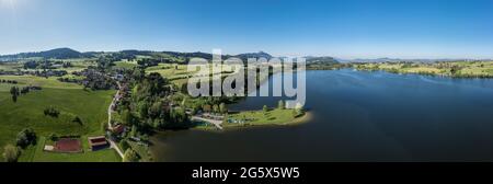 Panorama-Luftaufnahme über den Rottachsee in Richtung Gruenten, Dorf Petersthal mit kleinem Yachthafen, Allgau, Bayern, Deutschland. Stockfoto