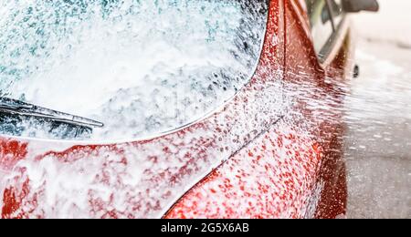 Detail auf Auto Heckscheibe mit Seifenschaum bedeckt, mehr Sprühen aus der Bürste, wenn in Autowäsche gewaschen Stockfoto