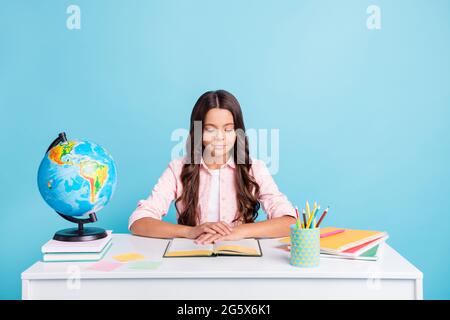 Foto von jungen ziemlich lächelnd fokussiert ruhig friedlich Mädchen sitzen Schreibtisch Lesung Hausaufgaben isoliert auf blauem Hintergrund Stockfoto