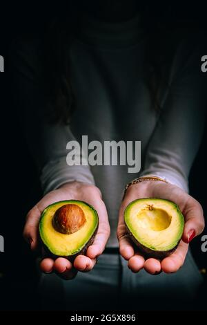 Avocado in weiblichen Händen geschnitten. Stockfoto