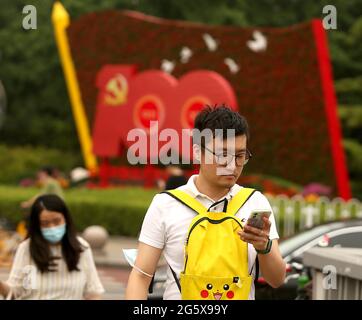 Peking, China. 30. Juni 2021. Am Mittwoch, dem 30. Juni 2021, warten Menschen an einer Kreuzung neben einer Plakatwand zum Gedenken an den 100. Jahrestag der Kommunistischen Partei Chinas in Peking. China begeht diese Woche den hundertsten Jahrestag seiner regierenden Kommunistischen Partei, indem es seinen wachsenden Einfluss im Ausland ankündigt, zusammen mit dem Erfolg bei der Bekämpfung von Korruption und Armut im eigenen Land. Foto von Stephen Shaver/UPI Credit: UPI/Alamy Live News Stockfoto