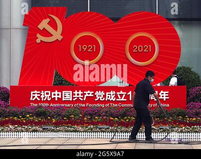 Peking, China. 30. Juni 2021. Ein Arbeiter wäßt Blumen in der Nähe einer Plakatwand zum Gedenken an den 100. Jahrestag der Kommunistischen Partei Chinas in Peking am Mittwoch, den 30. Juni 2021. China begeht diese Woche den hundertsten Jahrestag seiner regierenden Kommunistischen Partei, indem es seinen wachsenden Einfluss im Ausland ankündigt, zusammen mit dem Erfolg bei der Bekämpfung von Korruption und Armut im eigenen Land. Foto von Stephen Shaver/UPI Credit: UPI/Alamy Live News Stockfoto