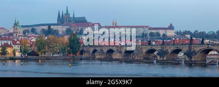 Prag - das Panorama der Karlsbrücke, Burg und Kathedrale von der Promenade über die Moldau in der Dämmerung. Stockfoto