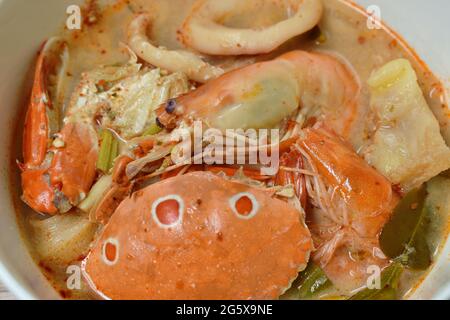 Gekochte Blumenkrabben und Garnelen verbinden Tintenfisch mit Dolly-Fisch in einer thailändischen, würzigen Suppe oder Fisch mit tom Yum auf der Schüssel Stockfoto