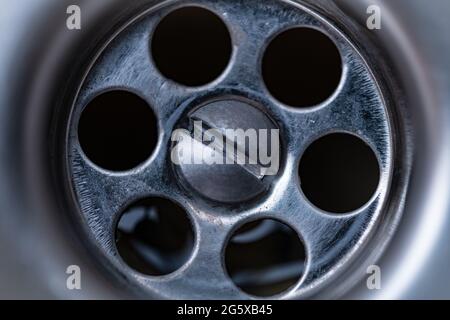 Makroaufnahme, wenn Wasser durch einen Abfluss in einem Waschbecken fließt. Stockfoto