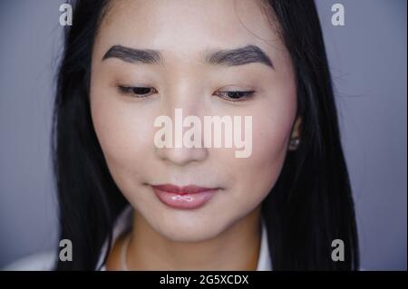 Porträt einer schönen asiatischen Frau während der Wimpern-Erweiterung Verfahren. Doppeltes Wimpern-Volumen vor und nach. Stockfoto