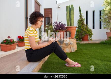 Die junge Frau nutzt ihr digitales Tablet im Freien Stockfoto