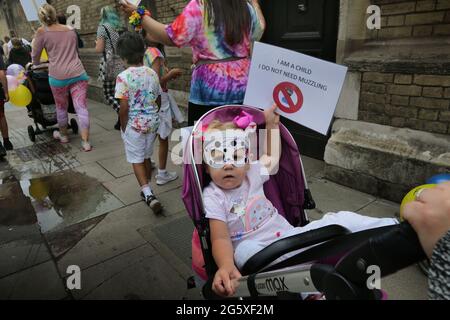 Ein junger Protestler in einem Kinderwagen hält ein Schild, auf dem steht, dass ich ein Kind bin, ich brauche während der Demonstration nicht zu muzzeln.Kinder und Eltern protestierten gegen erzwungene Impfungen für Kinder, Sperrbeschränkungen und keine Masken und Tests in Schulen. Stockfoto