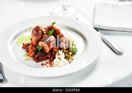 Gegrillte Würstchen in Honig-Bier-Sauce auf einem weißen Teller mit Kräutern. Deutsche, hausgemachte bayerische Küche. Selektiver Fokus. Stockfoto