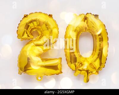 20 goldene Folienballon Zahlen Party Dekor auf weißem Hintergrund, Geburtstagskonzept mit Lichtern Stockfoto