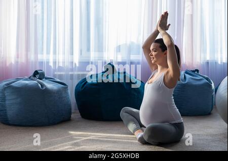 Schwangerin praktiziert Yoga. Eine Frau im dritten Trimester führt Pilates. Kurse zur Vorbereitung auf die Geburt. Warten auf das Baby. Stockfoto