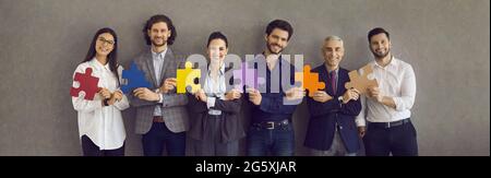 Team von glücklichen Geschäftsleuten stehen in Reihe und halten Puzzleteile Stockfoto
