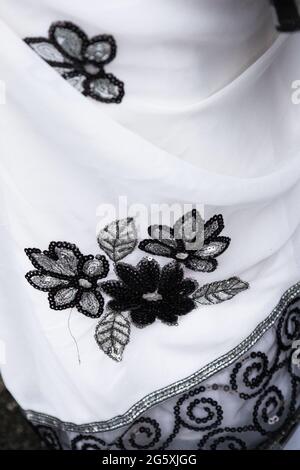 Zartes weißes Gewebe mit schwarzer Blumenstickerei und silbernem Rand eines Sari Stockfoto